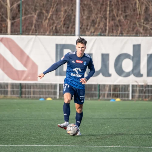 Na zdjęciu widać piłkarza w niebieskim stroju, który kontroluje piłkę na boisku podczas treningu.