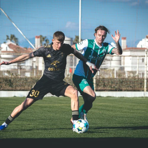 Na zdjęciu dwóch piłkarzy walczy o piłkę na boisku podczas meczu.