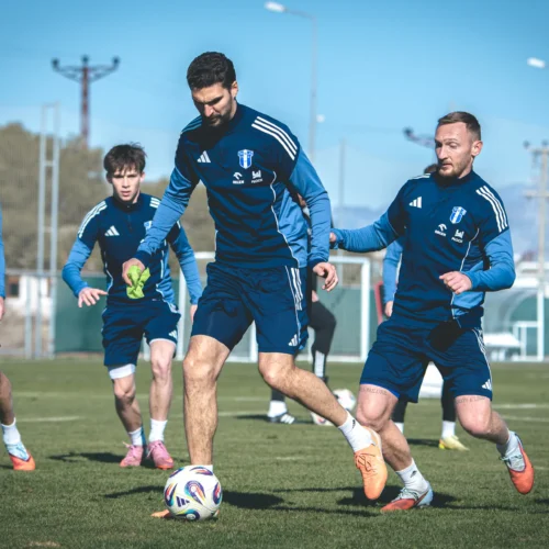 Zespół piłkarski podczas treningu na boisku, skupiony na doskonaleniu swoich umiejętności.