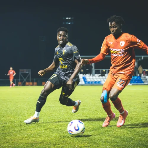 Dwaj piłkarze rywalizują ze sobą na boisku podczas meczu piłkarskiego.