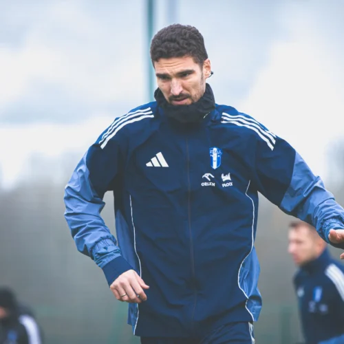 Na zdjęciu widać mężczyznę w sportowej odzieży, który trenuje na boisku w pochmurny dzień.