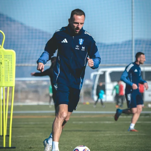 Na zdjęciu widać piłkarza w stroju sportowym biegnącego po boisku podczas treningu, z piłką przy nodze.