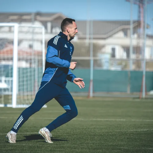 Na zdjęciu widoczny jest mężczyzna w niebieskim stroju biegający po boisku piłkarskim.