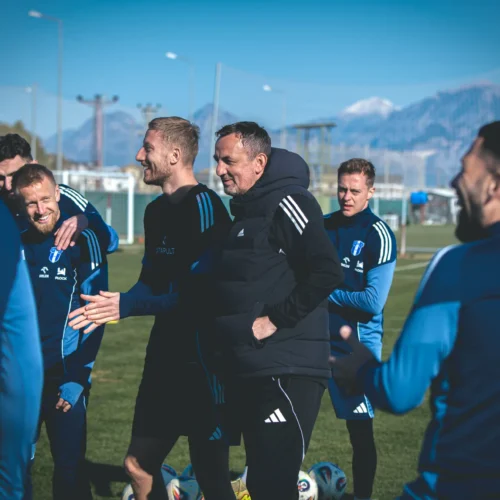 Zespół piłkarski cieszy się chwilą radości podczas treningu na boisku w słoneczny dzień.