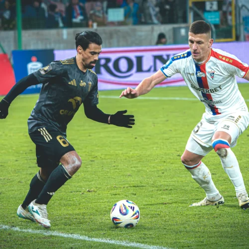 Na boisku piłkarskim dwóch zawodników walczy o piłkę podczas meczu.