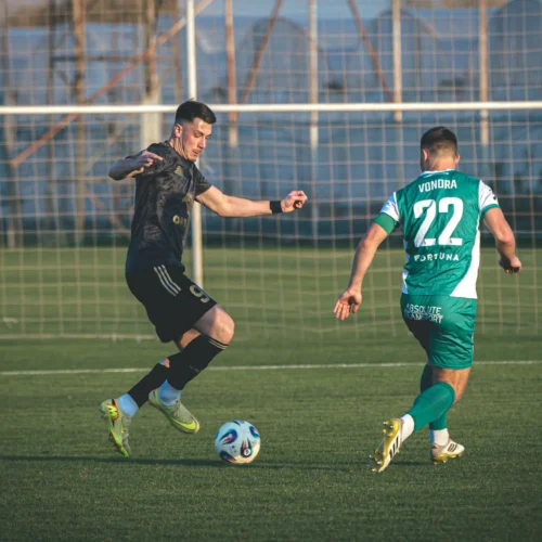 Na zdjęciu dwóch piłkarzy rywalizuje na boisku, jeden z nich właśnie odbiera piłkę.