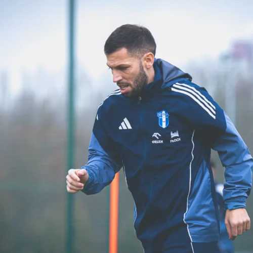 Na zdjęciu mężczyzna w sportowym stroju trenuje na boisku piłkarskim, skupiony na swoim biegu w trakcie treningu.