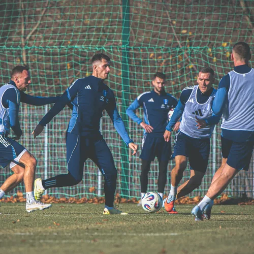 Na zdjęciu widać grupę piłkarzy trenujących na boisku, koncentrujących się na grze i interakcji podczas ćwiczeń.