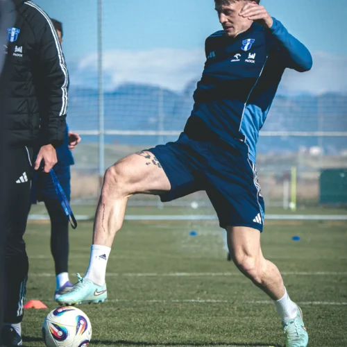 Na zdjęciu znajduje się zawodnik piłkarski w trakcie treningu, wykonujący dynamiczny ruch na boisku.