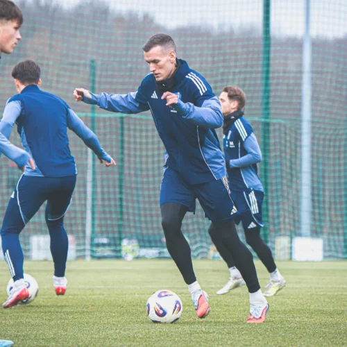 Na zdjęciu widać grupę młodych piłkarzy trenujących na boisku.