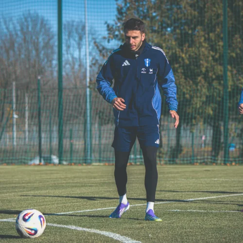 Dwóch piłkarzy trenuje na boisku, przygotowując się do nadchodzącego meczu.