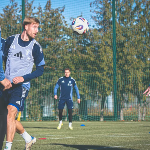Na zdjęciu widać czterech piłkarzy podczas treningu na boisku, z jednym zawodnikiem próbującym zagrać piłkę.