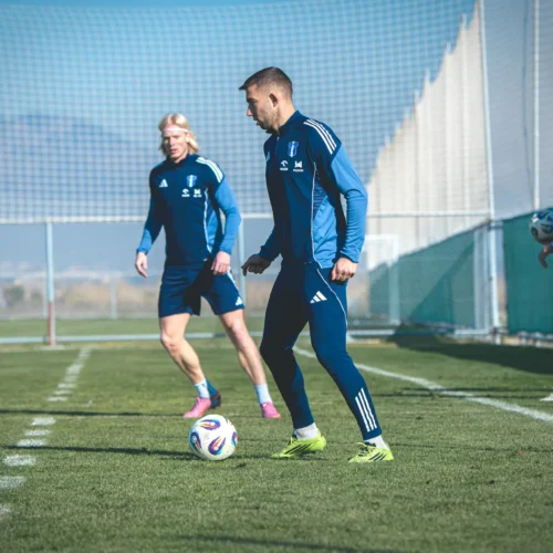 Na zdjęciu widać kilku piłkarzy w niebieskich strojach treningowych podczas treningu na boisku.