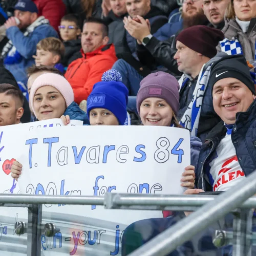 Na zdjęciu widać grupę kibiców na trybunach, którzy trzymają transparent z napisem wspierającym zawodnika T. Tavaresa.