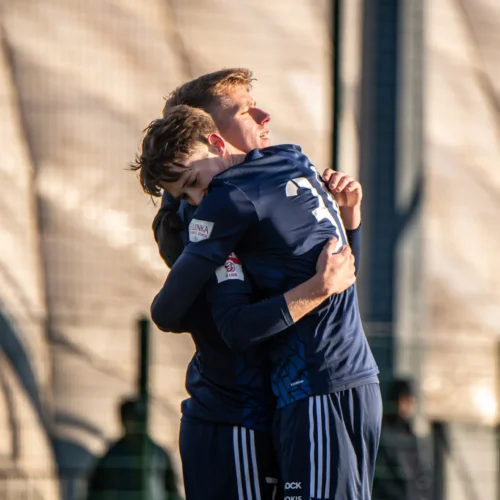 Dwóch młodych piłkarzy przytula się w radosnej chwili na boisku.