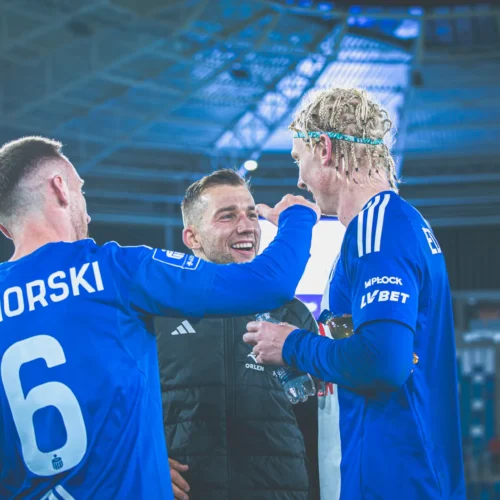 Zawodnicy w niebieskich strojach cieszą się i rozmawiają po meczu, wyrażając radość i entuzjazm.