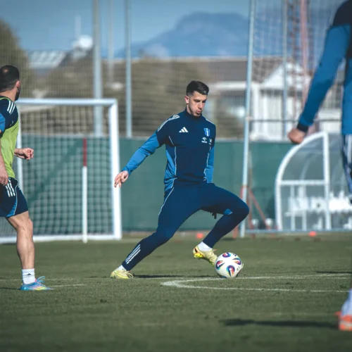 Zawodnicy grają w piłkę nożną podczas treningu na zielonym boisku.