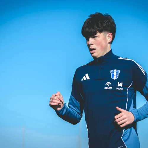 Młody sportowiec w niebieskim stroju biegowym ćwiczy na świeżym powietrzu w słoneczny dzień.